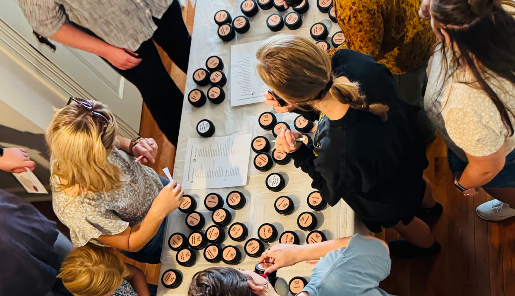 Guests gathered around the Wick Bar fragrance bar, smelling scent tins and choosing their blend.