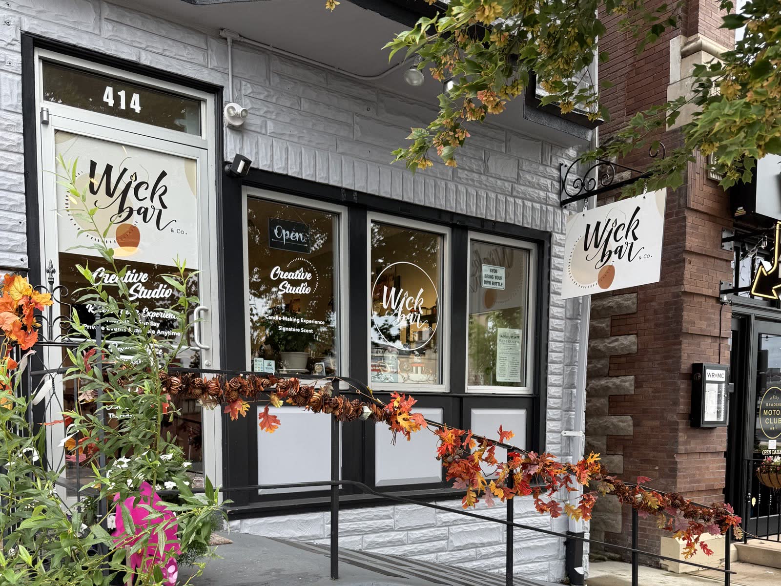 The Wick Bar & Co. storefront at 414 Penn Ave, West Reading — the hanging sign, the door and fall garland on the ramp.