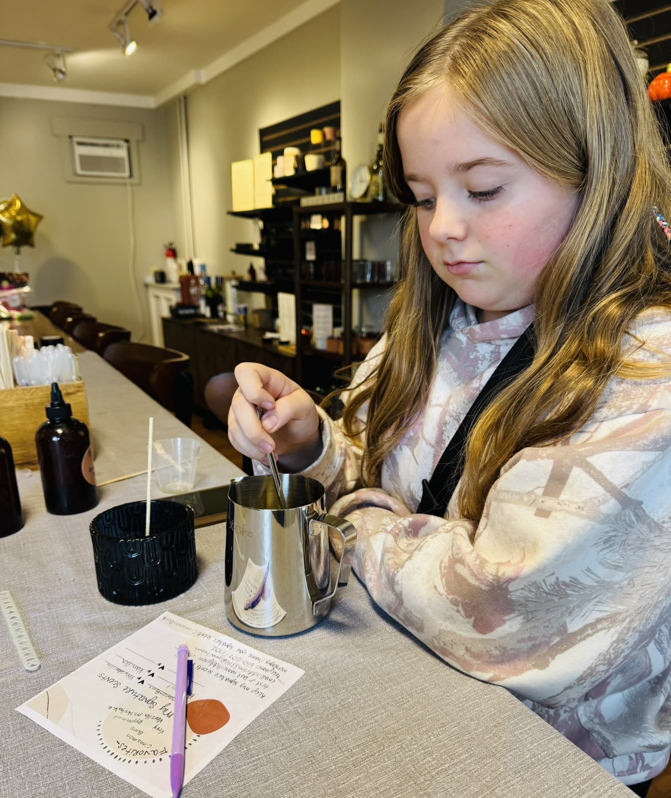 A young guest carefully stirring her candle wax at Wick Bar.