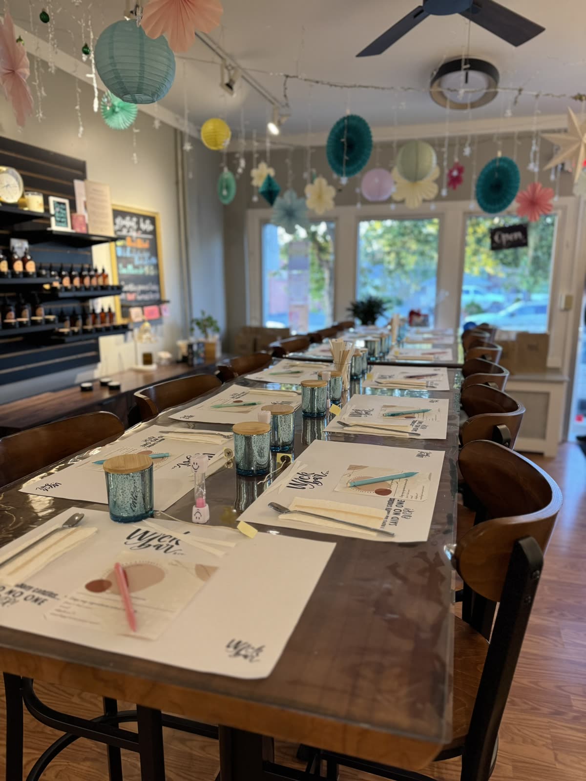 The Wick Bar studio set for a private party — place settings down the long tables under paper lanterns.