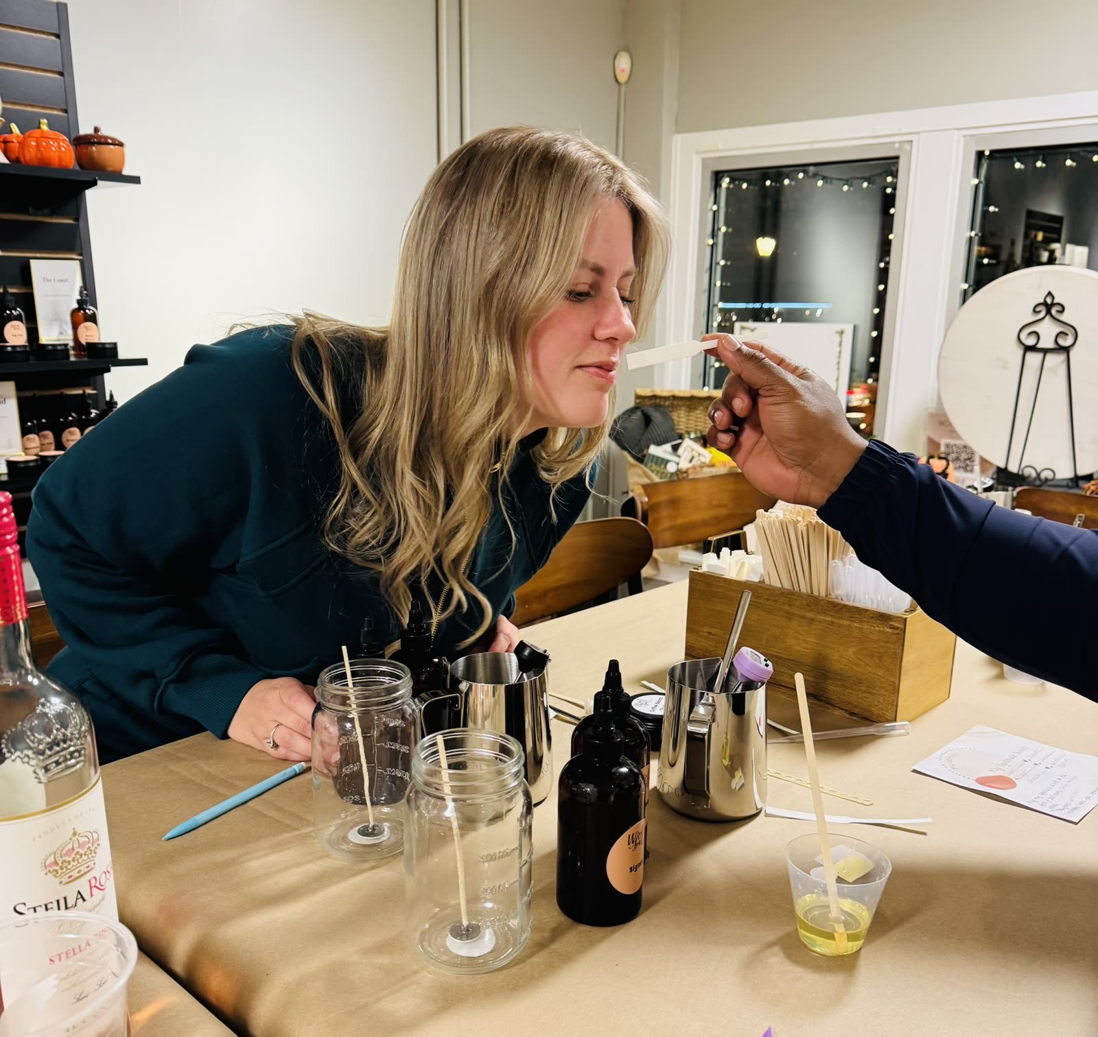 A guest smelling a fragrance at the Wick Bar table while choosing her scent.