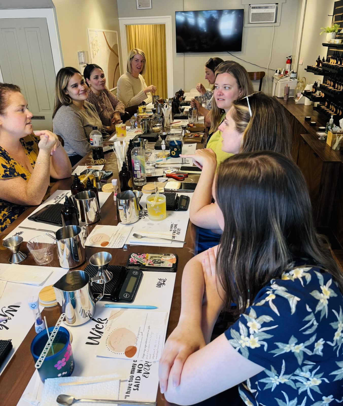 A group of coworkers around the long Wick Bar table, blending scents together.