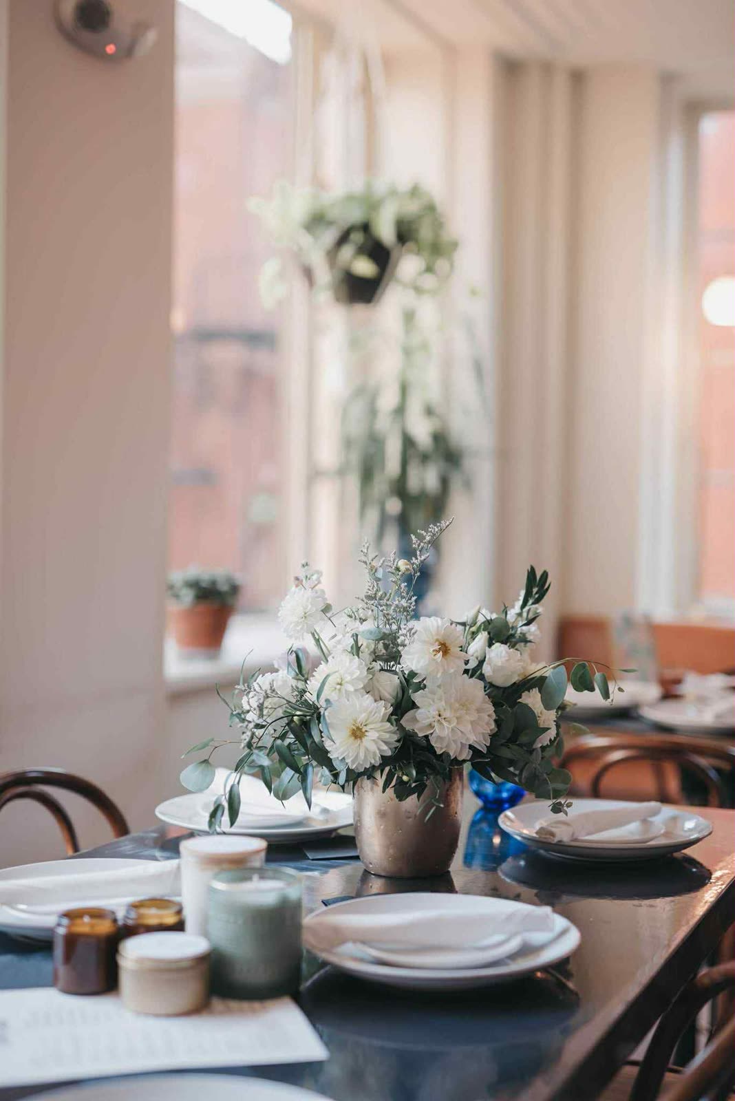 A reception table set with white florals and Wick Bar favor candles.
