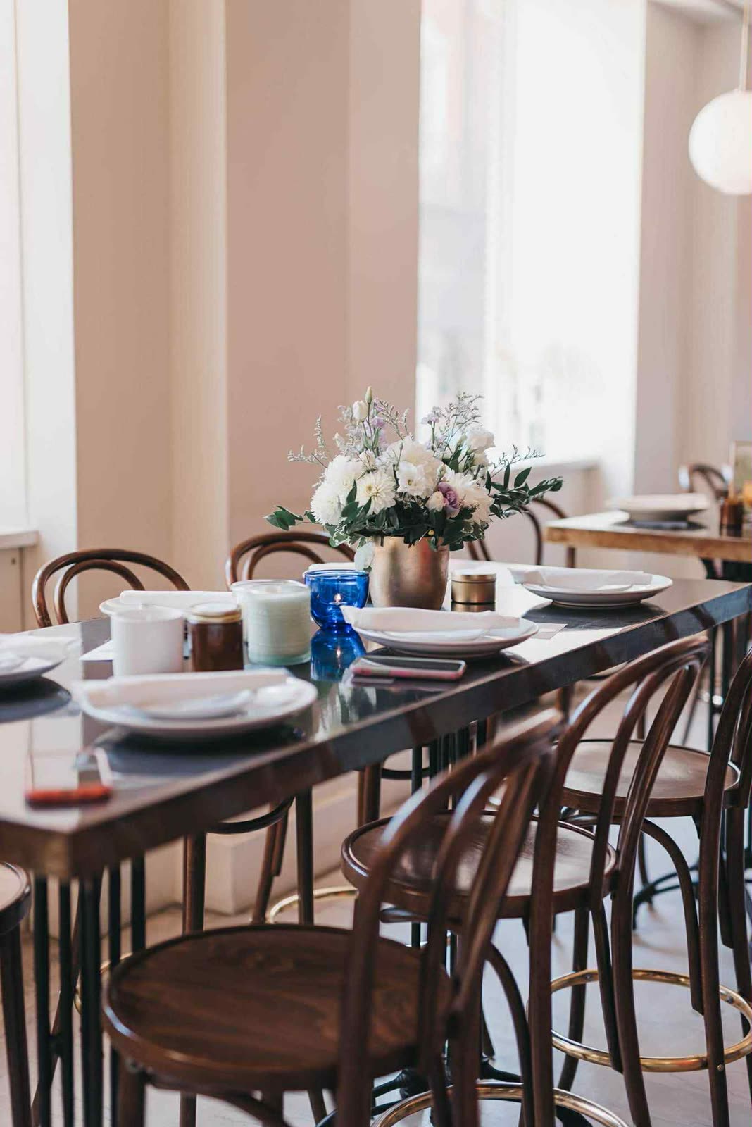 A long wedding table by the windows with favor candles at each place.