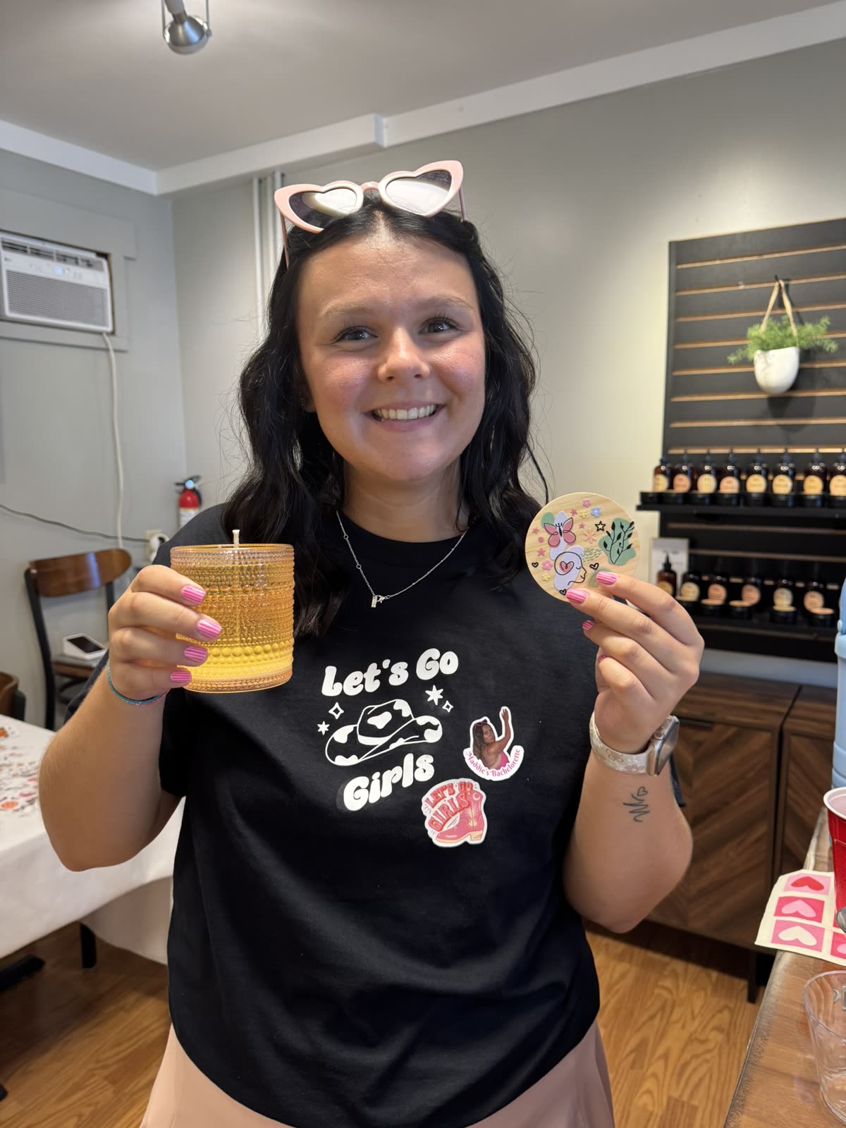 A bachelorette guest in a “Let’s Go Girls” shirt showing off her finished candle.