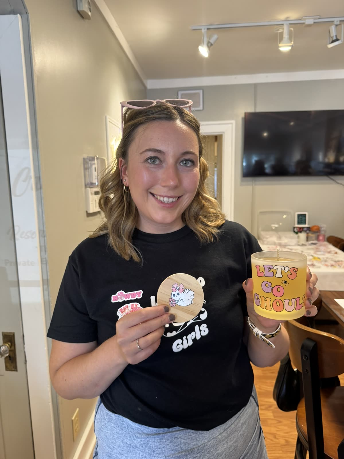 A bachelorette guest holding her “Let’s Go Ghouls” candle and wooden lid.