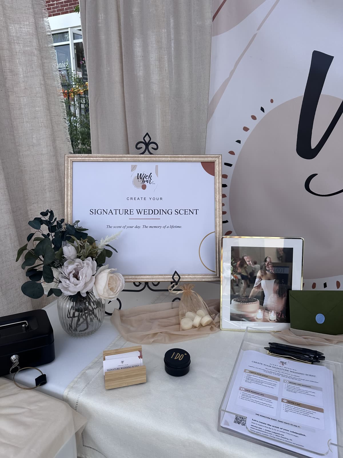 The Wick Bar “Create your Signature Wedding Scent” table, with florals, favors and a framed wedding photo.